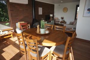 Cakebread Cottage في Encounter Bay: غرفة طعام مع طاولة وكراسي خشبية