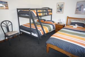 Cakebread Cottage في Encounter Bay: غرفة نوم بسريرين بطابقين وكرسي