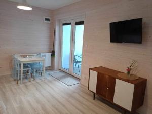 a living room with a table and a television on a wall at Rybacki Domek 50 metrów do morza! in Dziwnów
