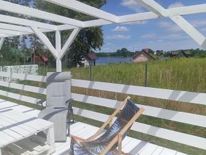 a chair sitting on a deck under a white pergola at GreenKris in Ostaszewo