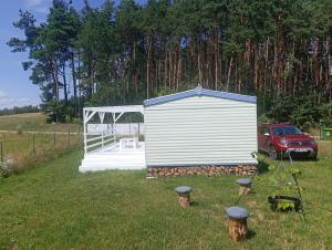 a small white shed in a field with a red car at GreenKris in Ostaszewo