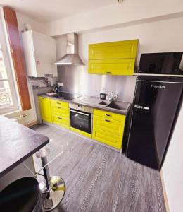 ヴァンドームにあるappartement calme, centre-villeのキッチン(黄色のキャビネット、黒い冷蔵庫付)