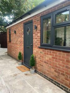 a brick house with a door and two potted plants at The Courtyard - By Casa Living in Canley