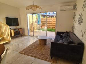 a living room with a couch and a tv at Maison Marsane côte Landaise in Lit-et-Mixe