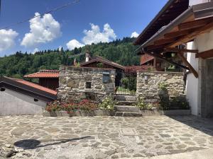 a building with a stone wall and flowers in front at Casa Scarbini in Savogna
