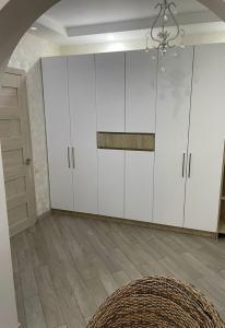 una cocina con armarios blancos y una lámpara de araña en sweet home, en Tiflis