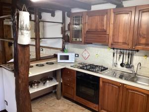a kitchen with wooden cabinets and a stove top oven at Casa Scarbini in Savogna