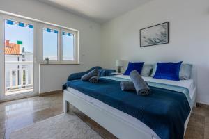 a bedroom with a bed with blue sheets and windows at PODVEZANEC in Dramalj