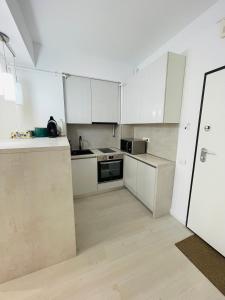 an empty kitchen with white cabinets and a refrigerator at Amely Apartments 305 by Wave Residence in Mamaia Nord