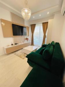 a living room with a green couch and a flat screen tv at Amely Apartments 305 by Wave Residence in Mamaia Nord