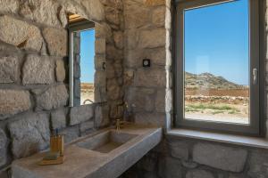 a stone bathroom with a sink and a window at Katoikia Milos Slow Living Homes in Mandrakia