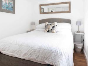 Schlafzimmer mit einem weißen Bett und einem Spiegel an der Wand in der Unterkunft The Pool House in Tywardreath