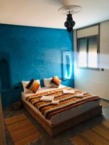 a bedroom with a large bed with a blue wall at Zakar Apartments in Mirleft