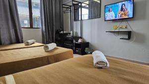 a hotel room with two beds and a tv on the wall at DLAYARAN HOTEL & CAFE in Kuala Rompin