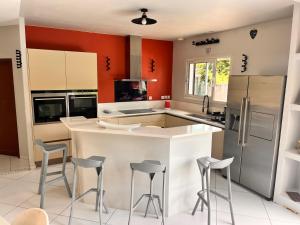 アンデルノ・レ・バンにあるvilla patio proche centre villeの赤い壁のキッチン、キッチンアイランド(スツール付)