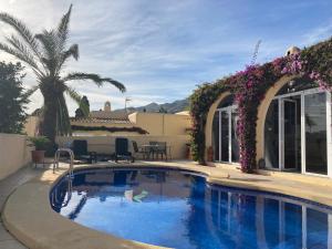 a swimming pool in a yard with purple flowers at Casa Tia, Mojácar with Private Pool and less than 5 minutes from beach! in Mojácar