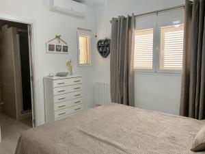 a bedroom with a bed and a dresser and windows at Casa Tia, Mojácar with Private Pool and less than 5 minutes from beach! in Mojácar +20 photos