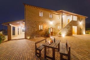 阿西西Agriturismo - La Campagna di San Francesco的一座石头房子，前面有两张木凳