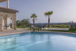 einen Pool mit 2 Stühlen und Palmen in der Unterkunft VILLA GALET-Saint Paul de Vence- Côte d'Azur-FRANCE in Saint-Paul-de-Vence