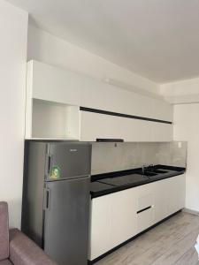 a kitchen with a stainless steel refrigerator and white cabinets at Il Sol Apartment in Lezhë