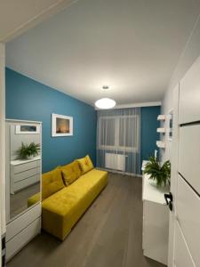 een woonkamer met een gele bank en blauwe muren bij AK Apartamenty Centrum in Białystok