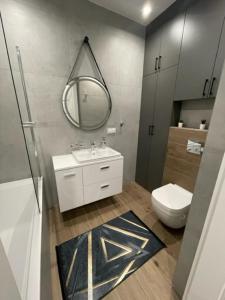 een badkamer met een wastafel, een toilet en een spiegel bij AK Apartamenty Centrum in Białystok +12 foto's