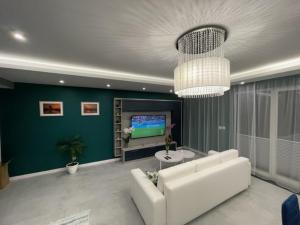 een woonkamer met een witte bank en een televisie bij AK Apartamenty Centrum in Białystok