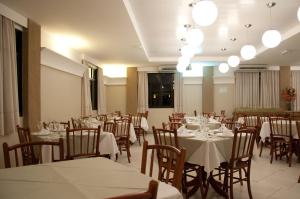 a dining room with tables and chairs and lights at Hotel Linhatur in Linhares +22 photos
