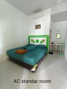 ein Schlafzimmer mit einem grünen Bett in einem weißen Zimmer in der Unterkunft AAL Homestay in Sabang