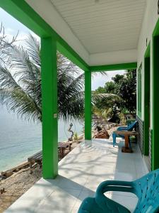 eine grüne Veranda mit Stühlen am Strand in der Unterkunft AAL Homestay in Sabang