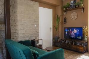 Una sala de estar con dos sillas verdes y un televisor. en Coin de nature en centre-ville, en Troyes