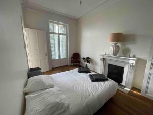a white bedroom with a bed and a fireplace at La Vie Dijonnaise in Dijon
