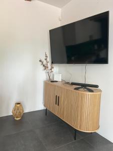 a flat screen tv on top of a wooden cabinet at Dom w lesie in Dzbądzek