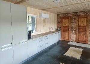 a kitchen with white cabinets and a brick wall at Peremehe saunamaja in Kauda