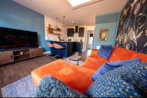 a living room with an orange couch and a flat screen tv at The Bradan - Troon - Coorie Doon Stays in Troon