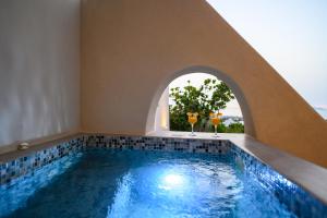 Una piscina cubierta con dos copas de vino en Galaria Serenity Suites, en Vóthon