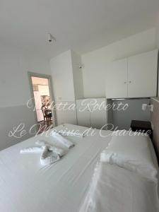 a bedroom with a bed with white sheets and a mirror at Villetta Roberto Le Macine di Charme - Pugnochiuso Resort in Vieste
