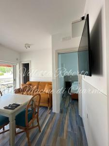 a living room with a table and a tv on a wall at Villetta Roberto Le Macine di Charme - Pugnochiuso Resort in Vieste