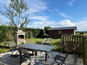 eine Terrasse mit einem Tisch und Stühlen sowie einem Holzofen in der Unterkunft Maison charmante à Bec-de-Mortagne avec jardin clôturé in Bec-de-Mortagne
