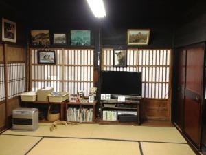 a living room with a flat screen tv in a room with atainment at Minshuku Yomoshirou in Nanto