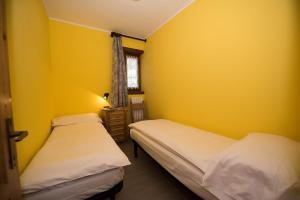 two beds in a room with yellow walls at Appartamento Baita Cusini Saroch in Livigno