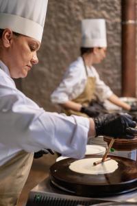 two chefs in a kitchen preparing food on a table at Astoria Resort in Riva del Garda