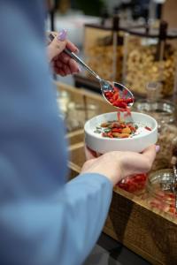 a person holding a bowl of food on a counter at Astoria Resort in Riva del Garda