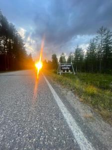 a sign on the side of a road with the sun at Laahtanen camping in Ristijärvi