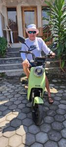 a man is sitting on a green scooter at Mugeni Homestay in Senggigi 