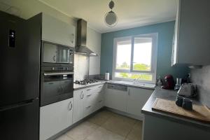 une grande cuisine avec des armoires blanches et une fenêtre dans l'établissement Jolie maison individuelle de Village avec Jardin, à Villeréal