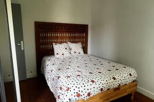 - une chambre avec un lit doté d'une tête de lit en bois et d'oreillers dans l'établissement Jolie maison individuelle de Village avec Jardin, à Villeréal