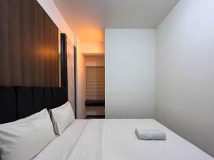 PampangにあるWarm and Cozy 2BR Vida View Makassar Apartment By Travelioのタオルが敷かれた白いベッドのある寝室
