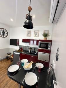 une cuisine avec une table avec des assiettes blanches dessus dans l'établissement Le cosy charmeur Climatisé avec patio, à Tours