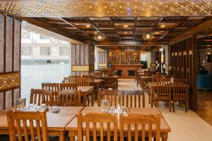 a restaurant with wooden tables and wooden chairs at Hotel Royal Airport in Kathmandu